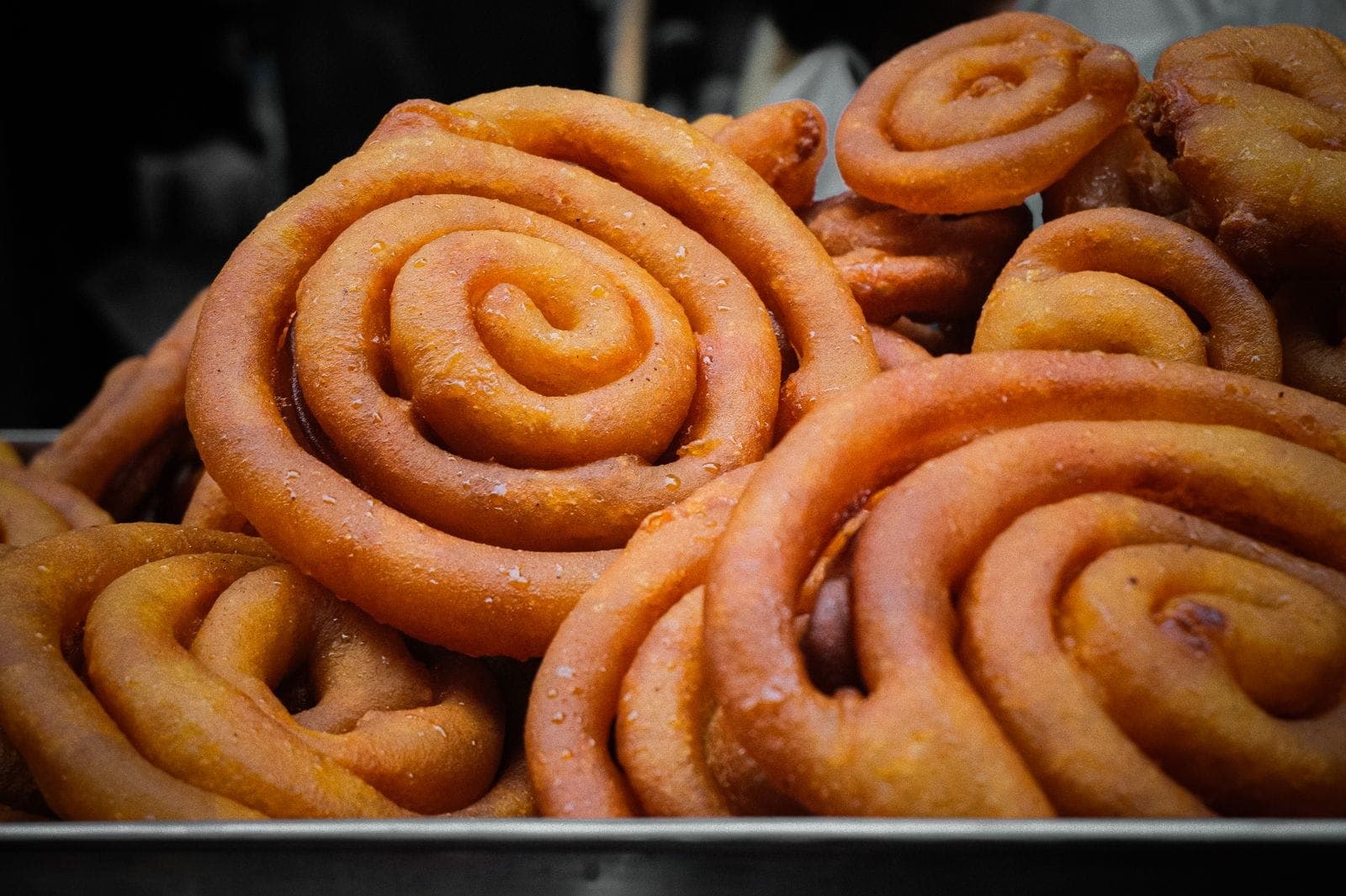 Freshly fried spiral jalebi piled in a steel tray
